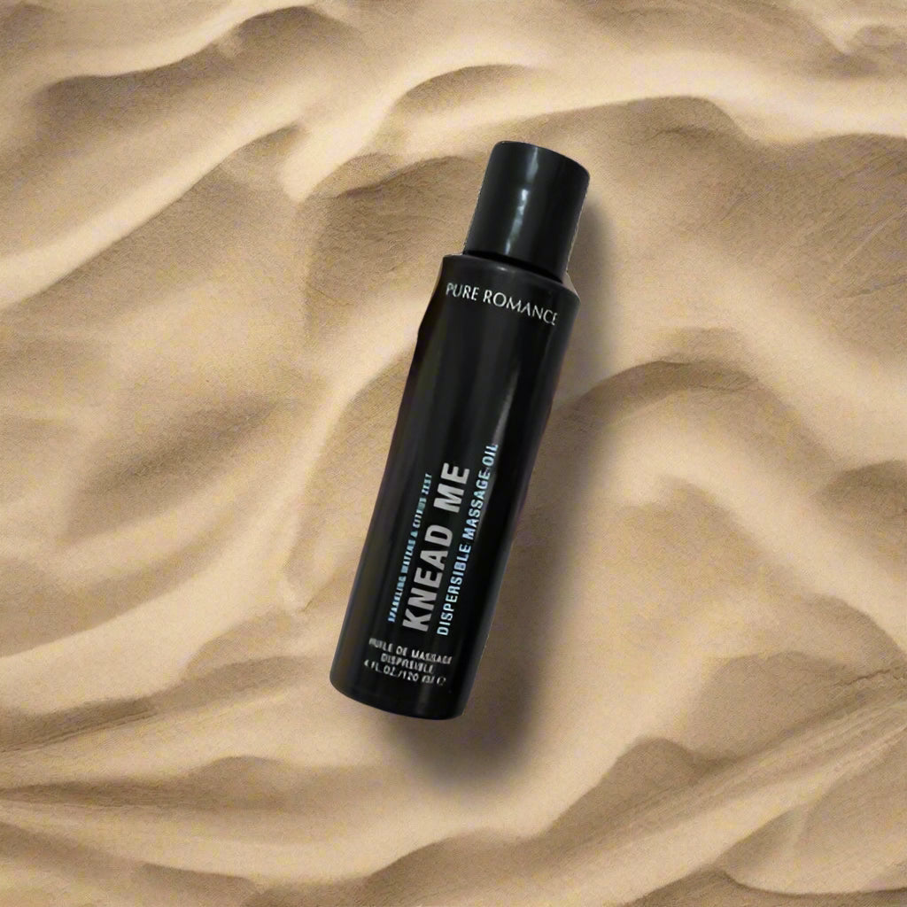 Pure Romance Knead me massage oil with flip top pop top lid sparkling waves and citrus zest fragrance on beach sand www.VALGINA.com