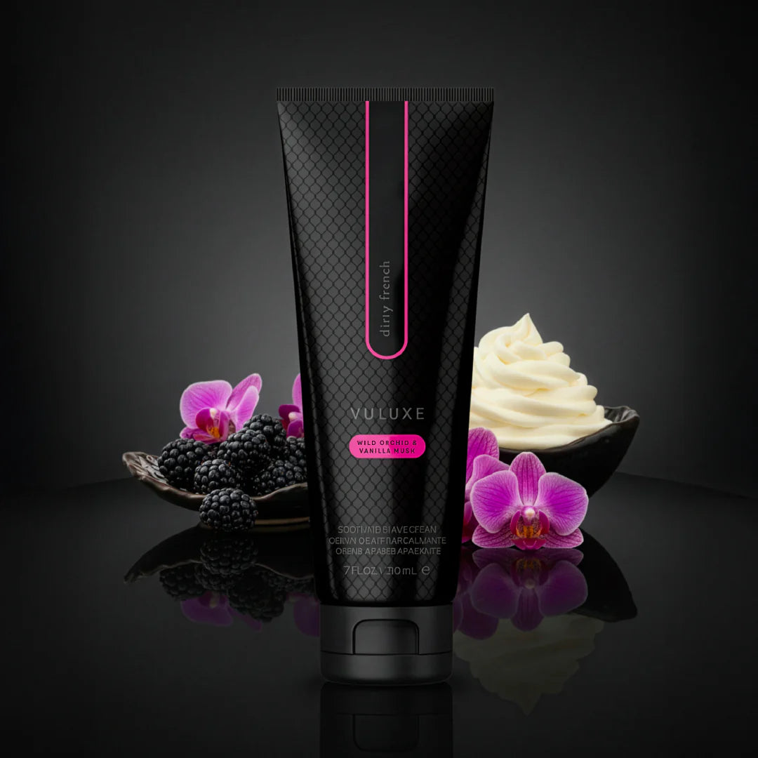 Black tube of VULUXE cream with pink accents on a dark background with flowers and cream. Vuluxe Coochy Shave Cream Rash free dirty french by pure romance www.VALGINA.com 