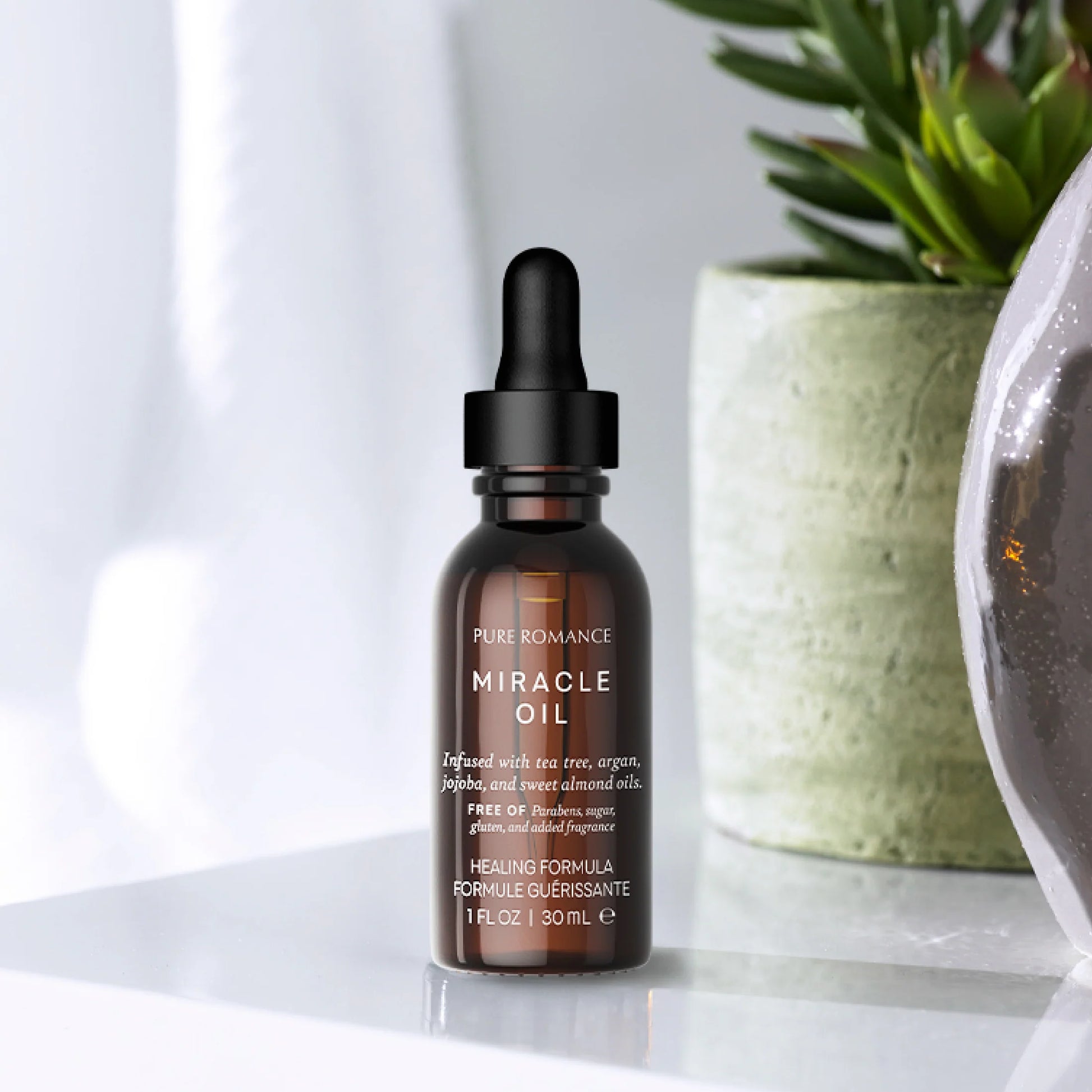 Brown bottle with dropper labeled 'Pure Romance Miracle Oil' on a white surface with a plant in the background. Miracle Oil healing blend of essential oils pure romance www.VALGINA.com 