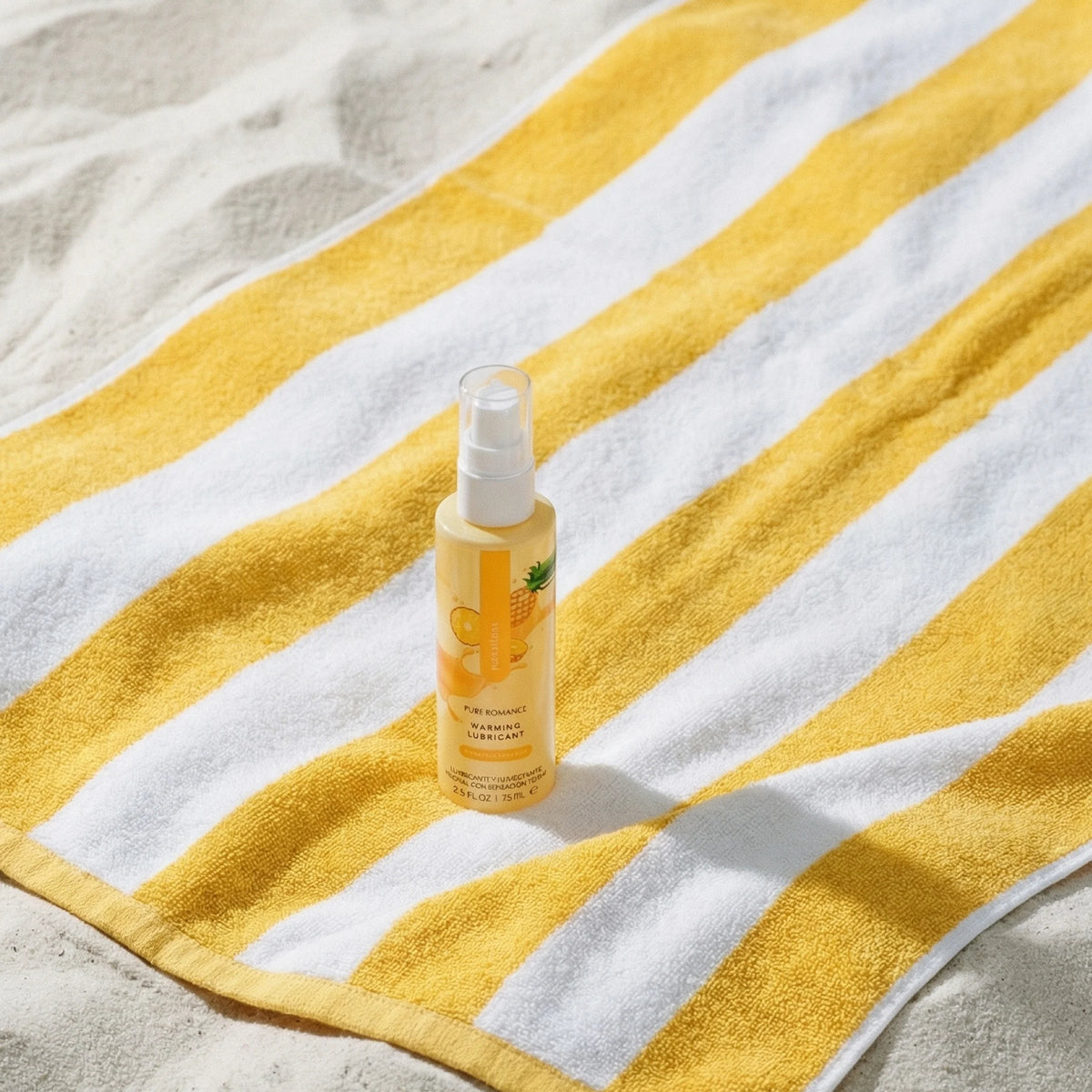 Spray bottle on a yellow and white striped towel on sand. sensations flavored warming lubricant for oral favors pineapple paradise pure romance www.VALGINA.com 