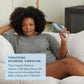 Woman sitting on a couch holding a device with text about a triple orgasm machine. t.o.m triple orgasm machine dual rabbit vibrator pure romance www.VALGINA.com 